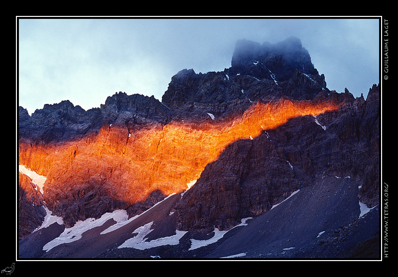 Alpes du Sud : Les premiers rayons du soleil éclairent, entre l'ombre de la Tête de la Fréma et les nuages, le Brec de Chambeyron
