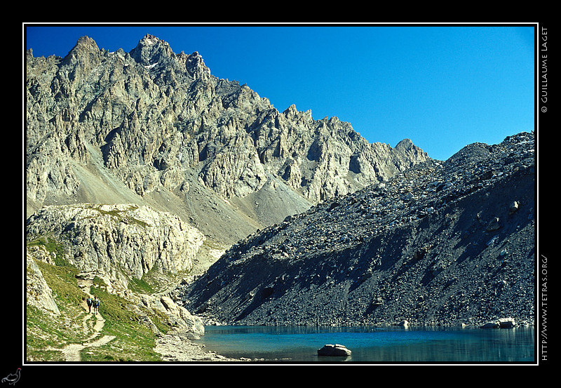 Alpes du Sud : Groupes de randonneurs sur un sentier le long du lac Long, devant les aiguilles de Chambeyron